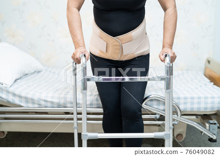 Asian lady patient wearing back pain support belt for orthopedic lumbar with walker. 76049082