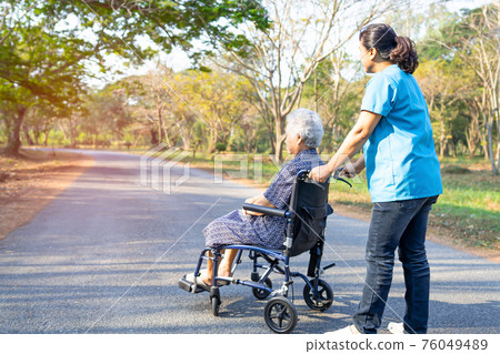 Doctor help and care Asian senior or elderly old lady woman patient sitting on wheelchair at park in nursing hospital ward, healthy strong medical concept. 76049489