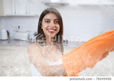Smiling woman cleaning dirty glass. Smiling woman cleaning dirty glass. 76049498