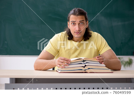 Young male student preparing for exams in the classroom Young male student preparing for exams in the classroom 76049599