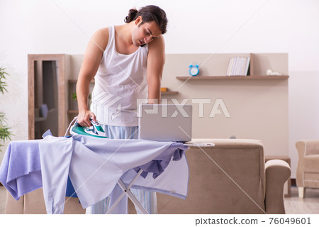 Young male employee ironing in the morning Young male employee ironing in the morning 76049601