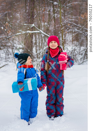 Happy children in a winter snow-covered forest with gift boxes. Happy children in a winter snow-covered forest with gift boxes. 76050217