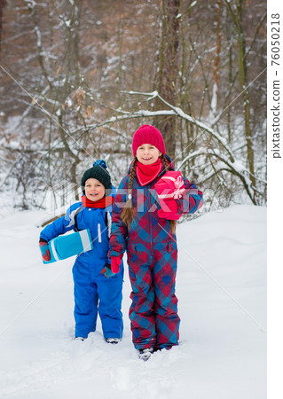 Happy children in a winter snow-covered forest with gift boxes. Happy children in a winter snow-covered forest with gift boxes. 76050218