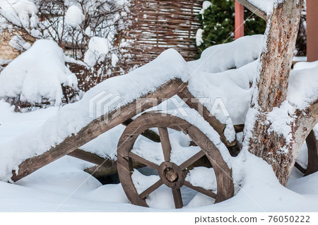 Snow-covered old yard in the village on a sunny winter day 76050222