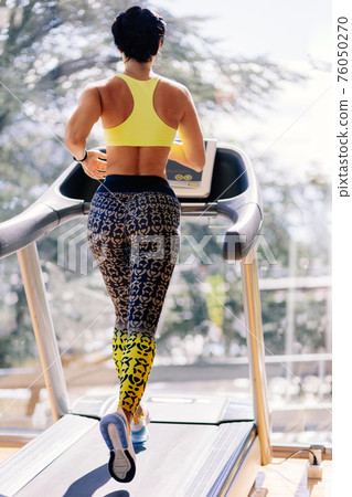 young attractive woman running on treadmill in sport gym young attractive woman running on treadmill in sport gym 76050270