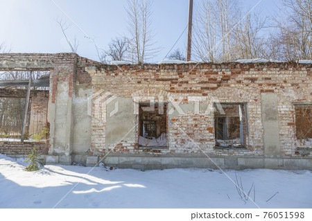 Part of the old facade of an abandoned stone house 76051598