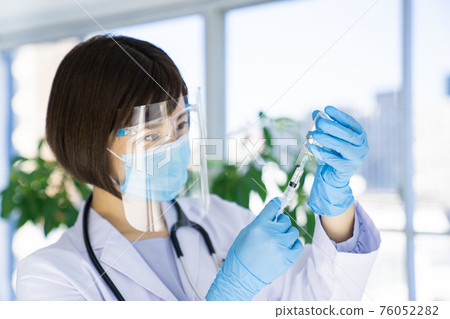 Doctor pulling vaccine from vial 76052282