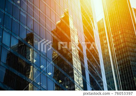 Skyscraper glass facades on a bright sunny day with sunbeams in the blue sky. Modern buildings in Moscow business district La Defense. Bottom up view 76053397