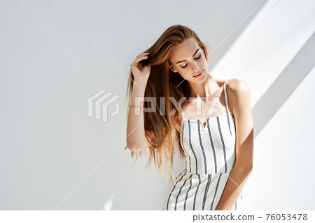 Portrait of pretty young woman posing in studio with sun lights on background 76053478