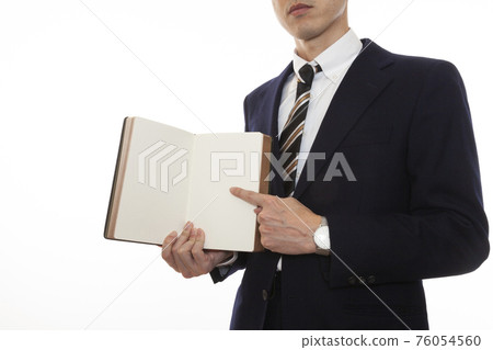一個穿西裝的男人指著一本打開的書 一個穿西裝的男人指著一本打開的書 76054560