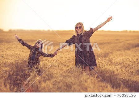young mother and her daughter at the wheat field on a sunny day young mother and her daughter at the wheat field on a sunny day 76055150