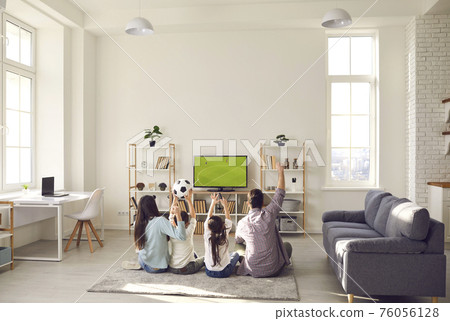Happy excited family with children watching soccer match on tv at home Happy excited family with children watching soccer match on tv at home 76056128