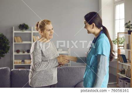 Happy senior patient getting acquainted with a friendly young nurse or physician 76056161