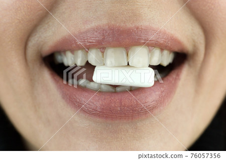 Chewing gum in a woman's teeth, close-up Chewing gum in a woman's teeth, close-up 76057356