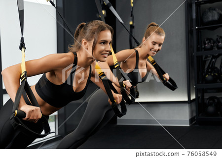 Young sporty women doing exercise with TRX system. 76058549