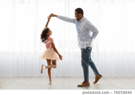 Black father and daughter dancing at home, full length shot 76059040