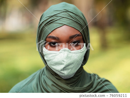 African Muslim Woman Wearing Protective Face Mask And Hijab Outdoors African Muslim Woman Wearing Protective Face Mask And Hijab Outdoors 76059211