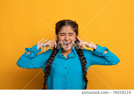 Angry indian woman plugging her ears with fingers and screaming 76059219