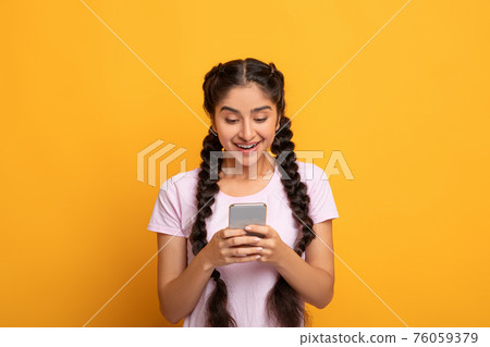 Smiling Indian woman using smart phone isolated on yellow background Smiling Indian woman using smart phone isolated on yellow background 76059379