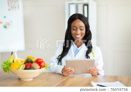 African American nutritionist working with tablet computer, giving online consultation at medical office, copy space 76059756