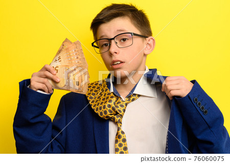A guy in a big classic suit on a yellow background holds a foreign currency, a child in glasses and a suit with a tie. A guy in a big classic suit on a yellow background holds a foreign currency, a child in glasses and a suit with a tie. 76060075