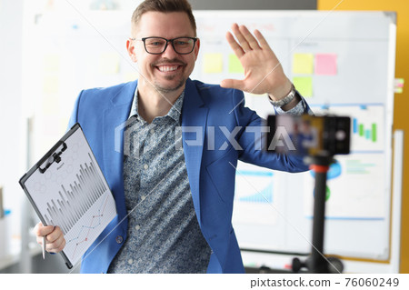 Businessman waving his hand to mobile phone camera Businessman waving his hand to mobile phone camera 76060249