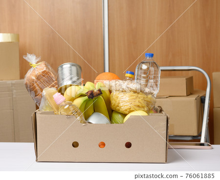 cardboard box with various products, fruits, pasta, sunflower oil in a plastic bottle and preservation 76061885