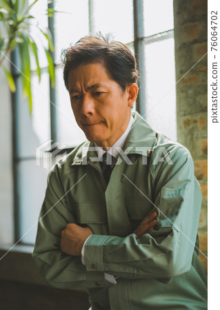 A man in work clothes and a tie 76064702
