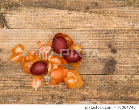 Painted eggs and onion husks on a wooden background. 76064746