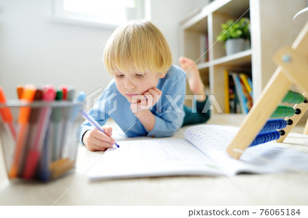 Elementary student boy doing homework at home. Child learning to count, solves arithmetic examples, using abacus. Math tutorial. Preparing preschooler baby for school. Education Elementary student boy doing homework at home. Child learning to count, solves arithmetic examples, using abacus. Math tutorial. Preparing preschooler baby for school. Education 76065184