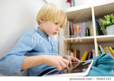Preschooler boy playing pc game by tablet. Overuse and addiction kids from gadgets. Preschooler boy playing pc game by tablet. Overuse and addiction kids from gadgets. 76065195