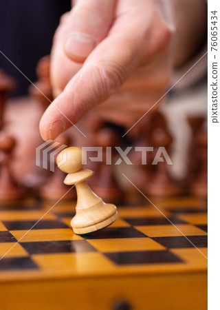 Old male employee playing chess at workplace 76065434