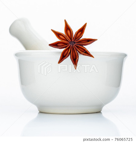 Closeup star anise in the white mortar isolated on white background . Food conceptual ingredients and medical. 76065725