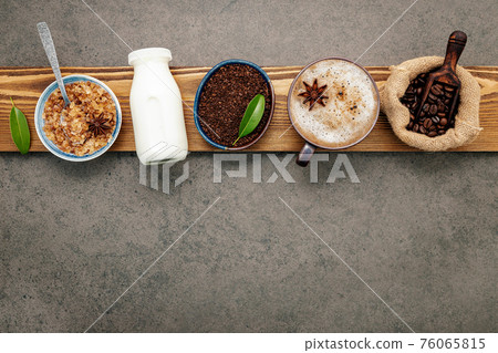 Roasted coffee beans with coffee powder and flavourful ingredients for make tasty coffee setup on dark stone background. 76065815