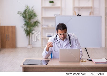 Young male doctor in telemedicine concept 76065901