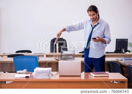Young male furious employee holding nun-chucks in the office Young male furious employee holding nun-chucks in the office 76066543