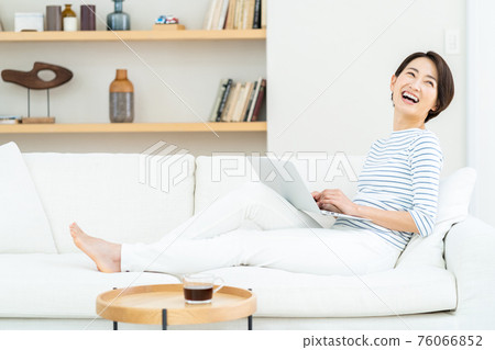 Woman playing laptop on the sofa Woman playing laptop on the sofa 76066852