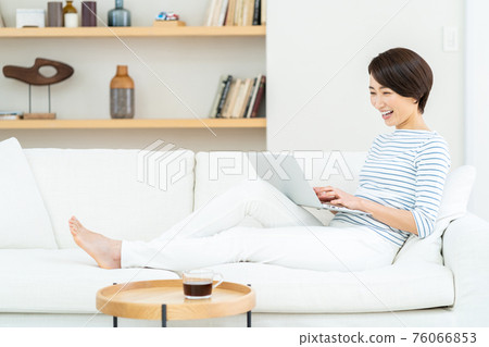 Woman playing laptop on the sofa Woman playing laptop on the sofa 76066853
