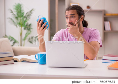 Young male student preparing for exams at home 76067683