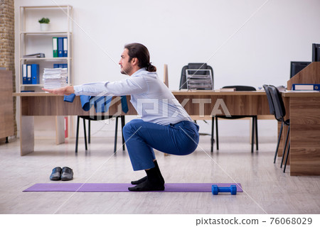 Young male employee doing sport exercises during break 76068029