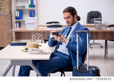 Young male employee preparing for trip in the office 76068039