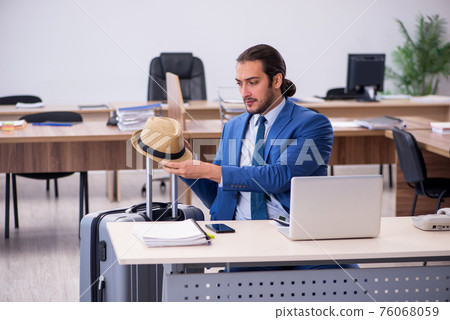 Young male employee preparing for trip in the office Young male employee preparing for trip in the office 76068059