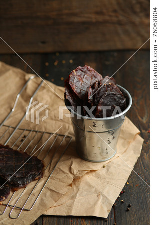 Homemade beef jerky seasoned with garlic, onion, pepper and salt. Jerky in a bucket on a wooden background 76068804