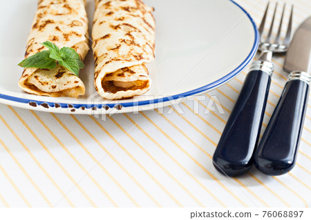 thin pancakes rolled crepes mint on a plate with knife and fork thin pancakes rolled crepes mint on a plate with knife and fork 76068897