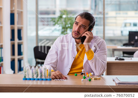 Young male chemist in drug synthesis concept Young male chemist in drug synthesis concept 76070052