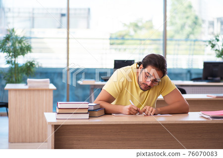 Young male student preparing for exams in the classroom Young male student preparing for exams in the classroom 76070083
