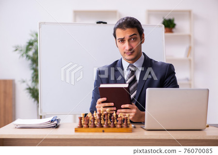Young male employee playing chess at workplace Young male employee playing chess at workplace 76070085