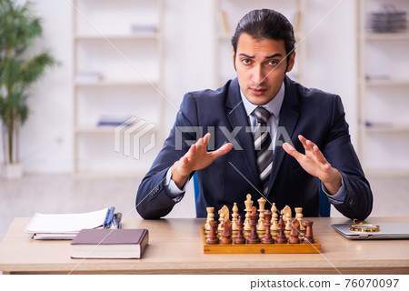 Young male employee playing chess at workplace Young male employee playing chess at workplace 76070097