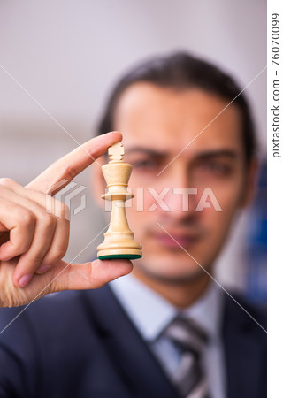 Young male employee playing chess at workplace Young male employee playing chess at workplace 76070099
