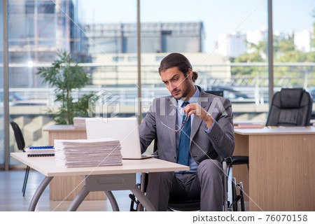 Young male employee in wheel-chair working in the office 76070158